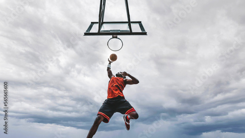 Basketball street player making a rear slam dunk - Athletic male training outdoor - Sport and competition concept