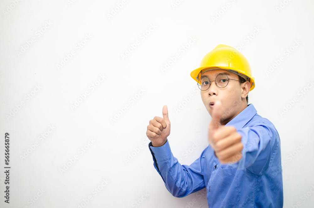 asian construction worker wearing yellow safety helmet and smiling and pointing finger with happy and shocked expression. billboard model advertisment concept. construction worker presenting something asian construction worker wearing yellow safety helmet and smiling and pointing finger with happy and shocked expression. billboard model advertisment concept. construction worker presenting something