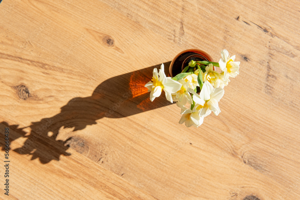 summer interior atmosphere. yellow flowers in a vase on a wooden background with a beautiful shadow. view from above. summer interior atmosphere. yellow flowers in a vase on a wooden background with a beautiful shadow. view from above.