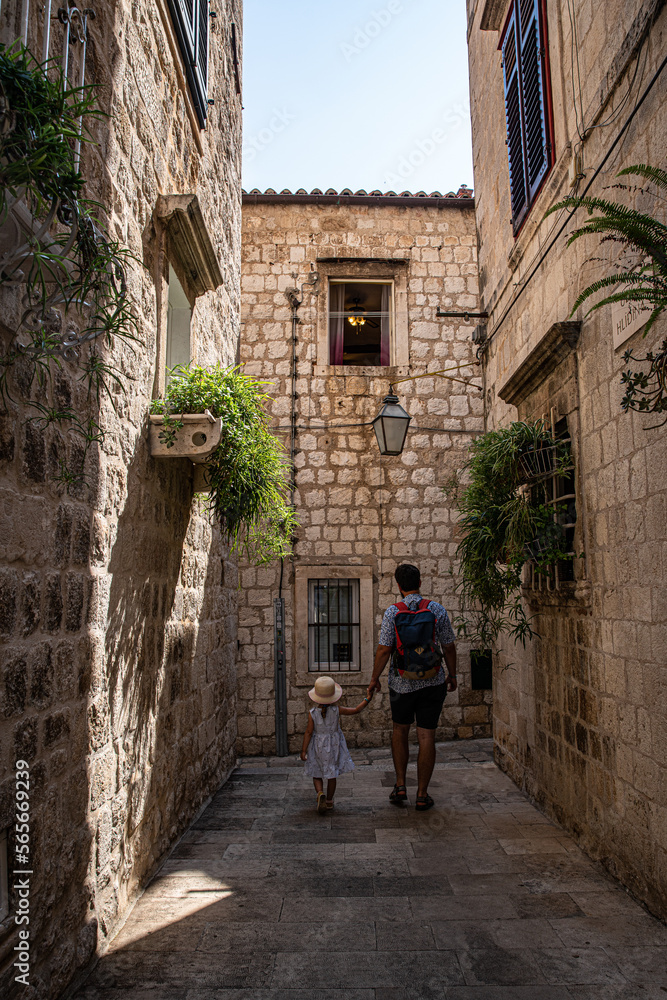 Father and little daughter walking on narrow streets of Mediterranean town.