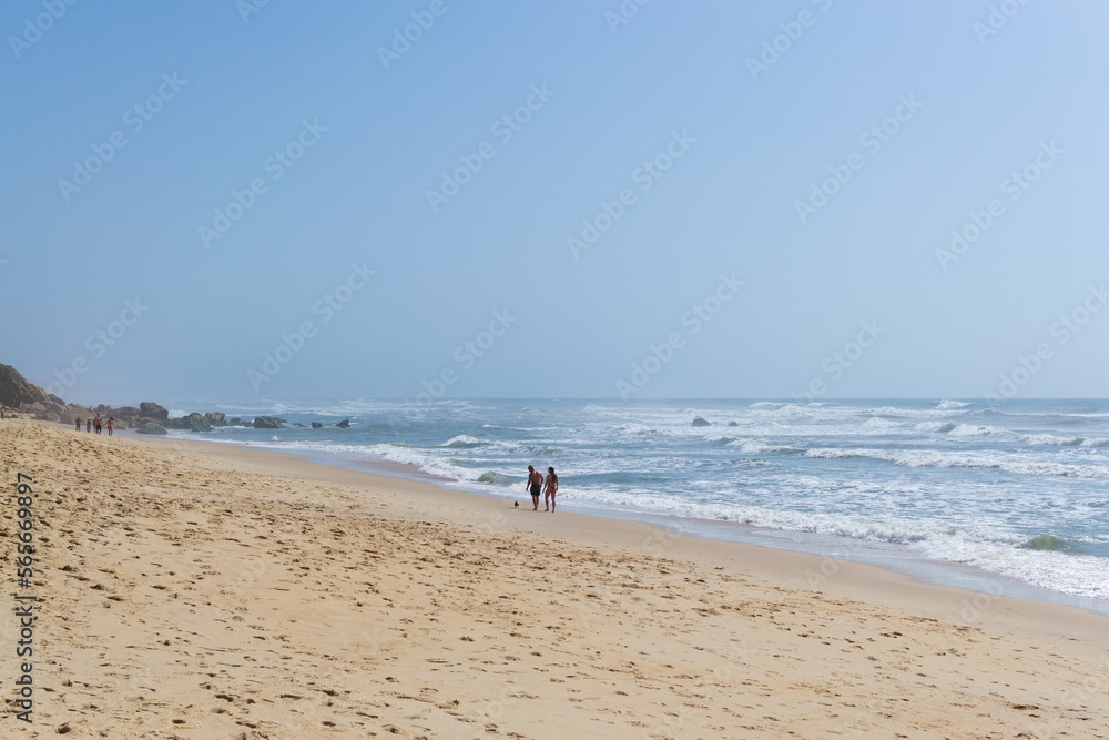 Beach by the ocean with people resting, vacation spot. Mountains, sea and waves. Travel to Europe Portugal.