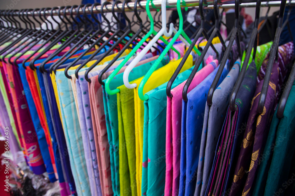 Colorful Saree clothes on hangers in a shop. Selective focus