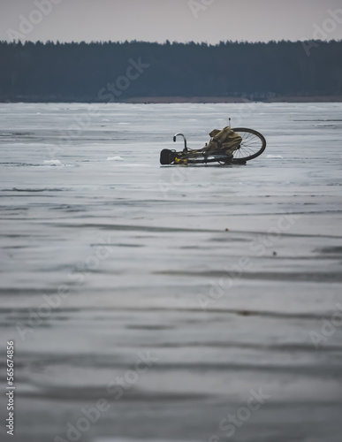 Minimalistic winter landscape on a frozen lake and a lonely lying bike, on a cloudy winter day