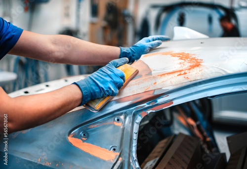 Mechanical repair of body paint. A mechanic repairs a car after an accident. Sand the primer before painting.