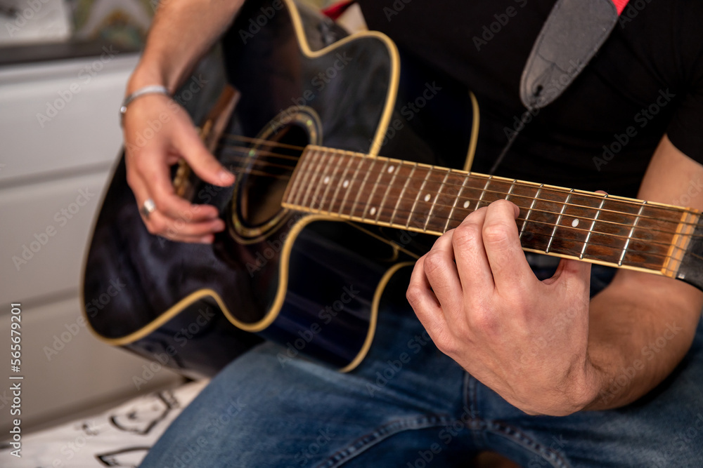 Obraz premium Young man is playing guitar while his girlfriend is singing. Detail of hand on guitar strings.