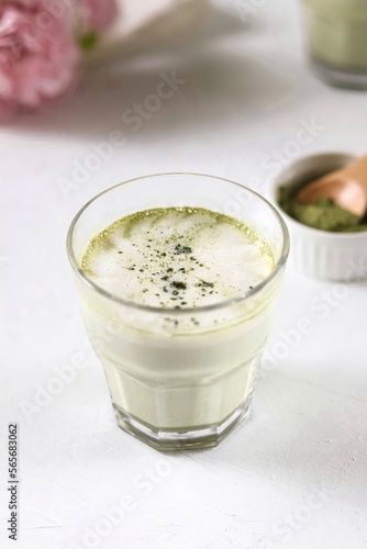 Matcha latte in a transparent glass with milk foam stands on a white background

