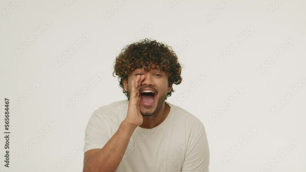 Excited Indian man screaming with hands near his mouth. Emotional curly guy yelling happily and showing thumbs up. Great news, win Excited Indian man screaming with hands near his mouth. Emotional curly guy yelling happily and showing thumbs up. Great news, win