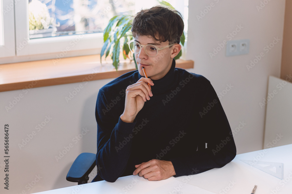 Naklejka premium Brown-haired architect is thinking hard about how to create new product designs for a new futuristic world. He works with his own creativity. Compass, pencil, ruler and paper. Creative home office