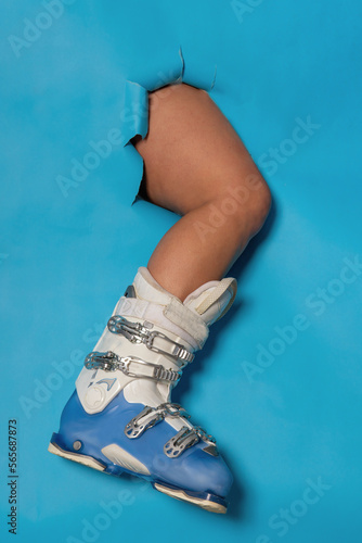 Leg of a girl in a ski boot on a blue background.