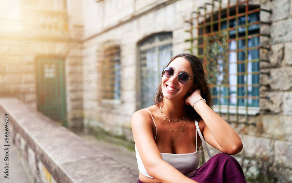 portrait young smiling brazilian woman sitting outdoors in a public park with old mansion in the background