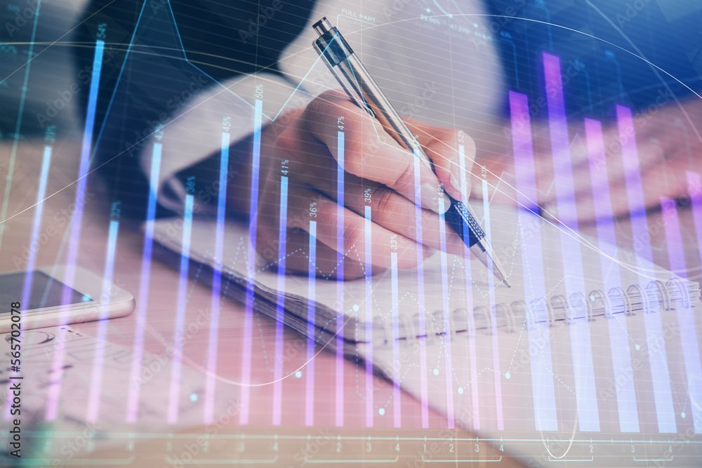 A woman hands writing information about stock market in notepad. Forex chart holograms in front. Concept of research. Multi exposure A woman hands writing information about stock market in notepad. Forex chart holograms in front. Concept of research. Multi exposure