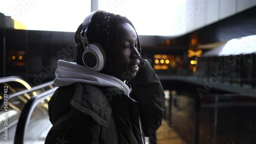 young african american woman with dreadlocks, wears headphones to listen to music, dancing walking in the city