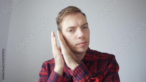 The young man asks to speak more quietly, because they are sleeping next to him. A man is talking on a video link. View from the laptop webcam. The man explains with gestures. High quality 4k footage