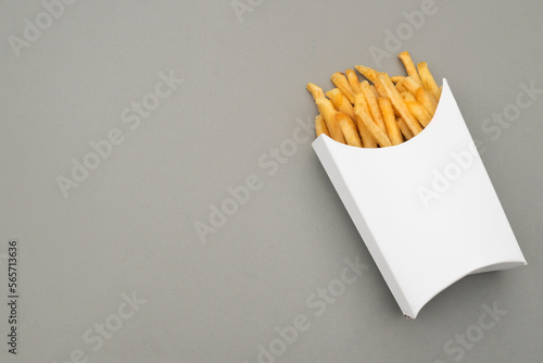 Eine Portion Pommes Frites in einer weißen Pappschachtel. Grauer Papierhintergrund und die Verpackung bieten Copy Space. Mock Up. photo
