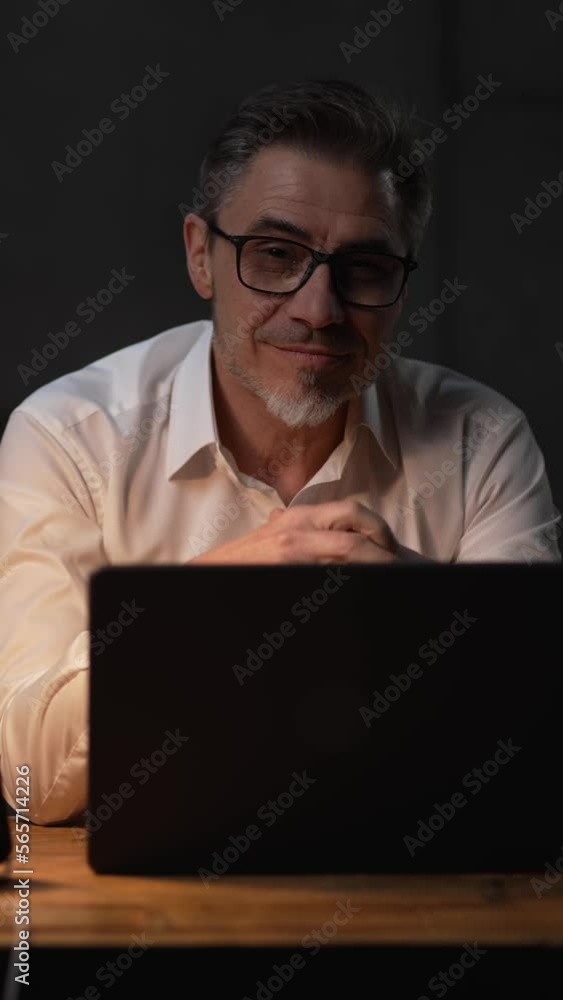 Businessman sitting at desk with laptop computer. Entrepreneur working late in office. Happy middle aged, mid adult, man in his 40s or 50s in business casual, smiling . Businessman sitting at desk with laptop computer. Entrepreneur working late in office. Happy middle aged, mid adult, man in his 40s or 50s in business casual, smiling .
