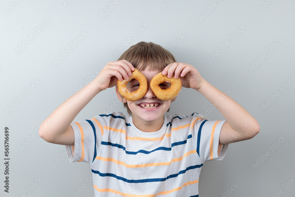The blond boy looks through the donuts like through glasses. Portrait of a smiling child with donuts The blond boy looks through the donuts like through glasses. Portrait of a smiling child with donuts