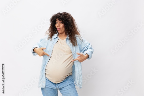 Pregnant woman smile maternity happiness finger pointing at her belly on a white isolated background in a t-shirt with a blue shirt