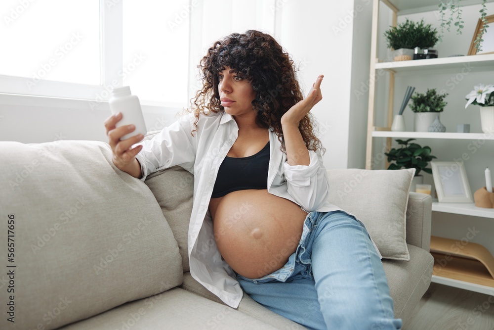 Pregnant woman surprise blogger takes vitamins and medicines sitting on the couch at home freelancer in the last month of pregnancy lifestyle before childbirth Pregnant woman surprise blogger takes vitamins and medicines sitting on the couch at home freelancer in the last month of pregnancy lifestyle before childbirth