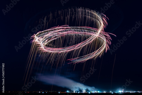 Two gliders during night air show releasing fireworks and paint serpentines in the night sky.
