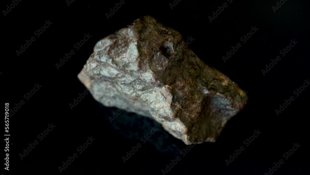 Rotating Of An Iron Meteorite. black background on a mirror base. Top view Rotating Of An Iron Meteorite. black background on a mirror base. Top view