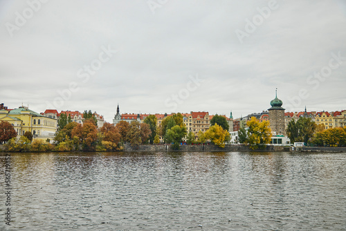 Wide view of architecture in Prague. We see colorful buildings  Vltava river and autumn trees.