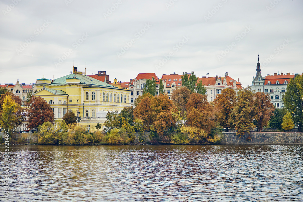 View of architecture in Prague. We see buildings, Vltava river and autumn trees.