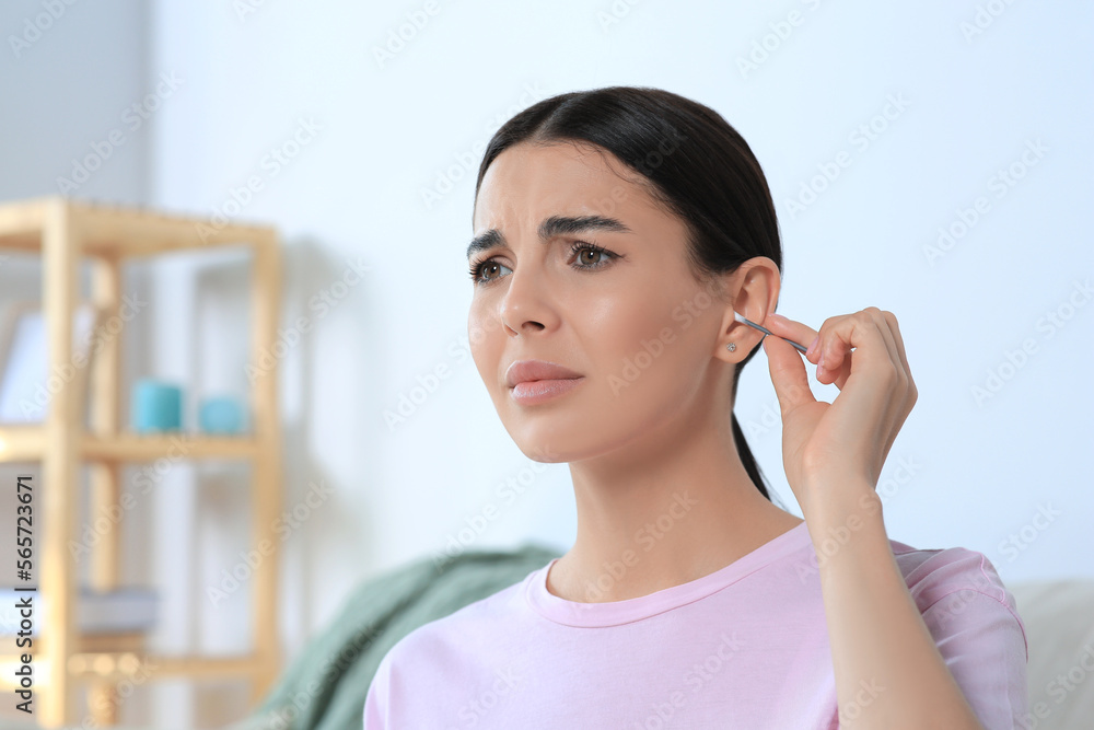 Young woman cleaning ear with cotton swab at home Young woman cleaning ear with cotton swab at home