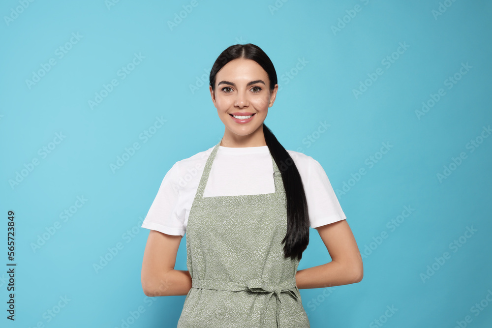 Young woman in grey apron on light blue background, Young woman in grey apron on light blue background,