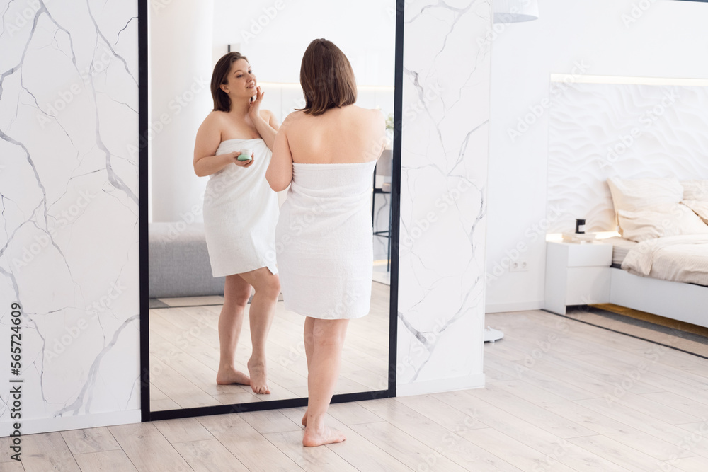 Adult woman apply body cream look in mirror at home. Beauty and lifestyle concept. Adult woman apply body cream look in mirror at home. Beauty and lifestyle concept.