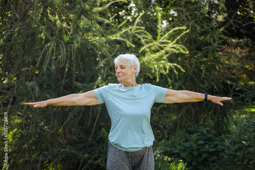 Elderly woman with short hair practicing yoga and tai chi outdoors. Old female meditating.
