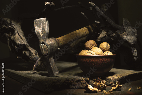 Still life with hammer and walnuts. Crack walnuts. Walnut shell. Chop nuts with a hammer. Still life in a low key. photo