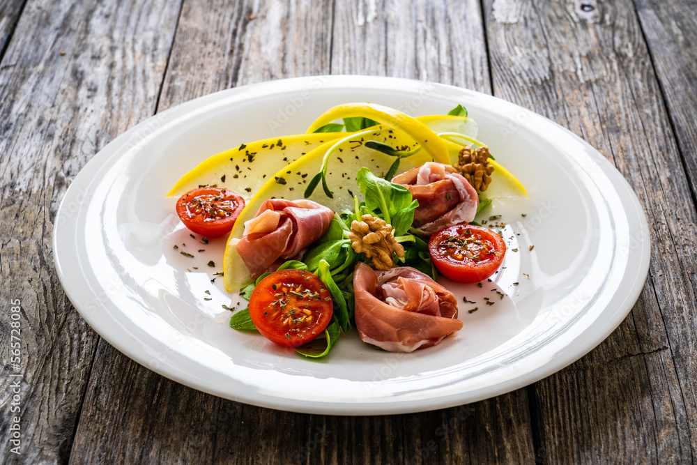 Tasty salad - prosciutto crudo, melon and fresh vegetables on wooden table
Tasty salad - prosciutto crudo, melon and fresh vegetables on wooden table