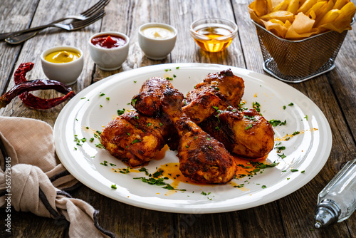 Barbecue chicken drumsticks with French fries on wooden table 