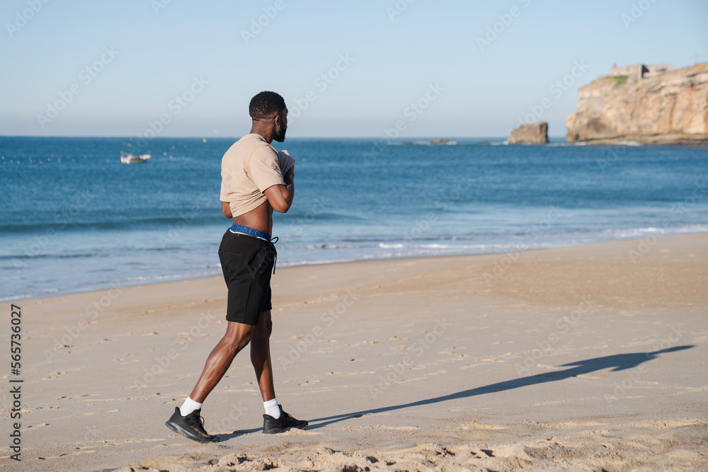 young man walking after running on the beach young man walking after running on the beach