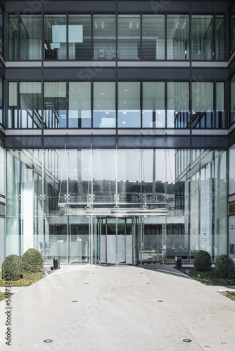 Main facade with access door to an office building with a lot of metal and glass