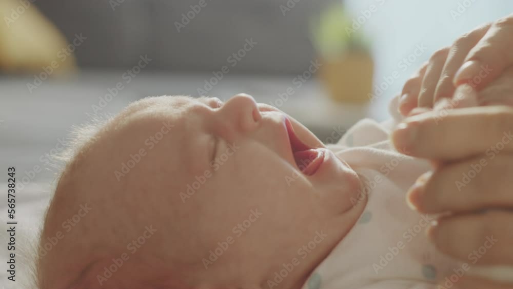 Close-up view of a little newborn baby crying loudly in slow-motion while lying on the bed, mom touching her hands and trying to calm her Close-up view of a little newborn baby crying loudly in slow-motion while lying on the bed, mom touching her hands and trying to calm her