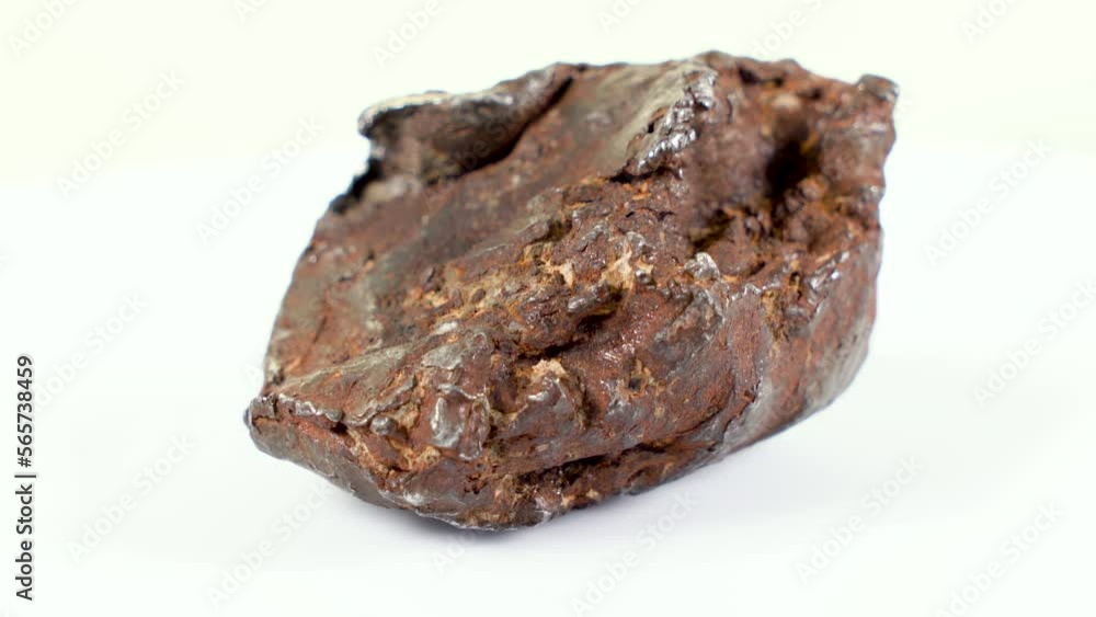 Rotating Of An Iron Meteorite. White background on a white base. general plan. Rust on the surface Rotating Of An Iron Meteorite. White background on a white base. general plan. Rust on the surface