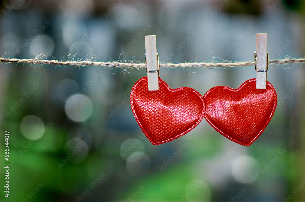 Two red textile hearts hanging on a jute string on clothespins on a natural background. A symbol of love. To close. Copy space. Two red textile hearts hanging on a jute string on clothespins on a natural background. A symbol of love. To close. Copy space.