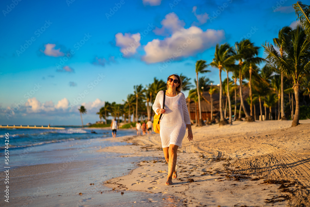 Obraz premium Beach holiday - woman walking on sunny, tropical beach in the morning