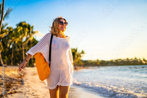 Beach holiday - woman walking on sunny, tropical beach in the morning 

