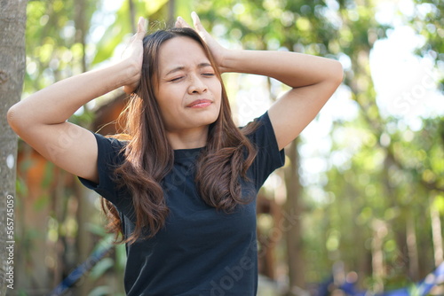 Asian woman thinking hard causing headache green forest background