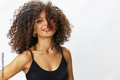 Beautiful woman with curly afro hair posing on a white isolated background smile happiness in jeans and black top emotion, hand signs, copy space