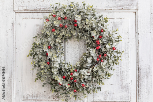 Green and red berry Christmas wreath on an old, antique door