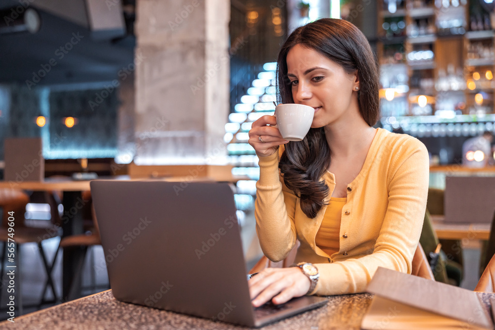 Female entrepreneur relaxing at coffee shop and reading email on her laptop Female entrepreneur relaxing at coffee shop and reading email on her laptop