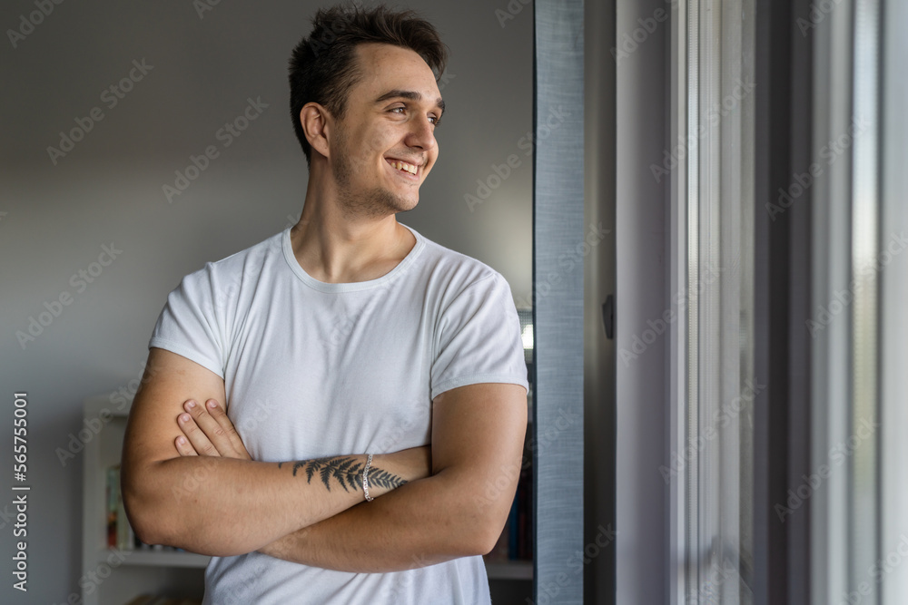 Portrait of one young adult caucasian man stand by the window at home Portrait of one young adult caucasian man stand by the window at home