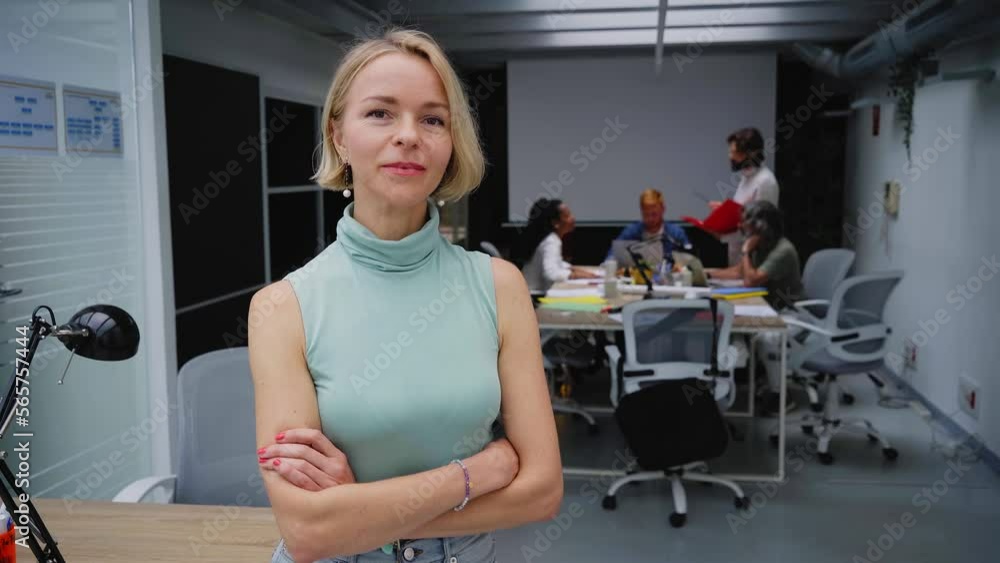 Serious confident blonde Caucasian business woman looking at camera standing with arms crossed in office. Executive CEO professional manager posing for business portrait. Serious confident blonde Caucasian business woman looking at camera standing with arms crossed in office. Executive CEO professional manager posing for business portrait.