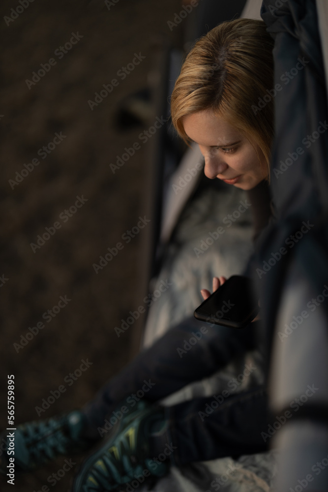 Woman talking on the phone in a tent while camping at sunset Woman talking on the phone in a tent while camping at sunset