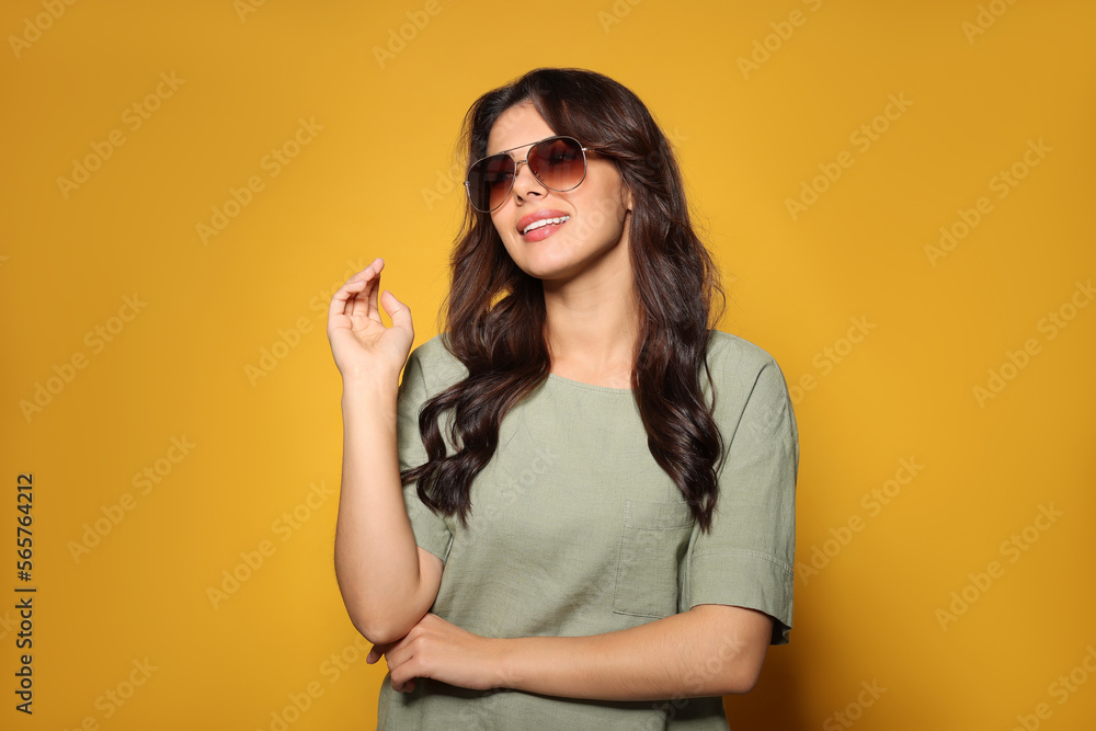 Happy beautiful woman with stylish sunglasses on orange background Happy beautiful woman with stylish sunglasses on orange background