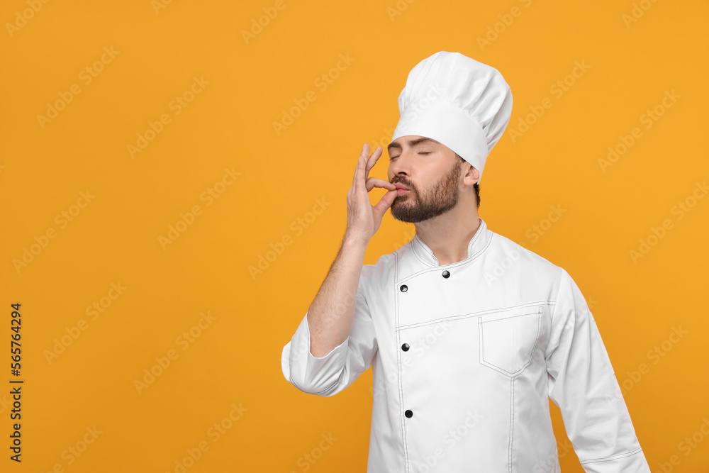 Mature chef showing delicious gesture on orange background, space for text Mature chef showing delicious gesture on orange background, space for text