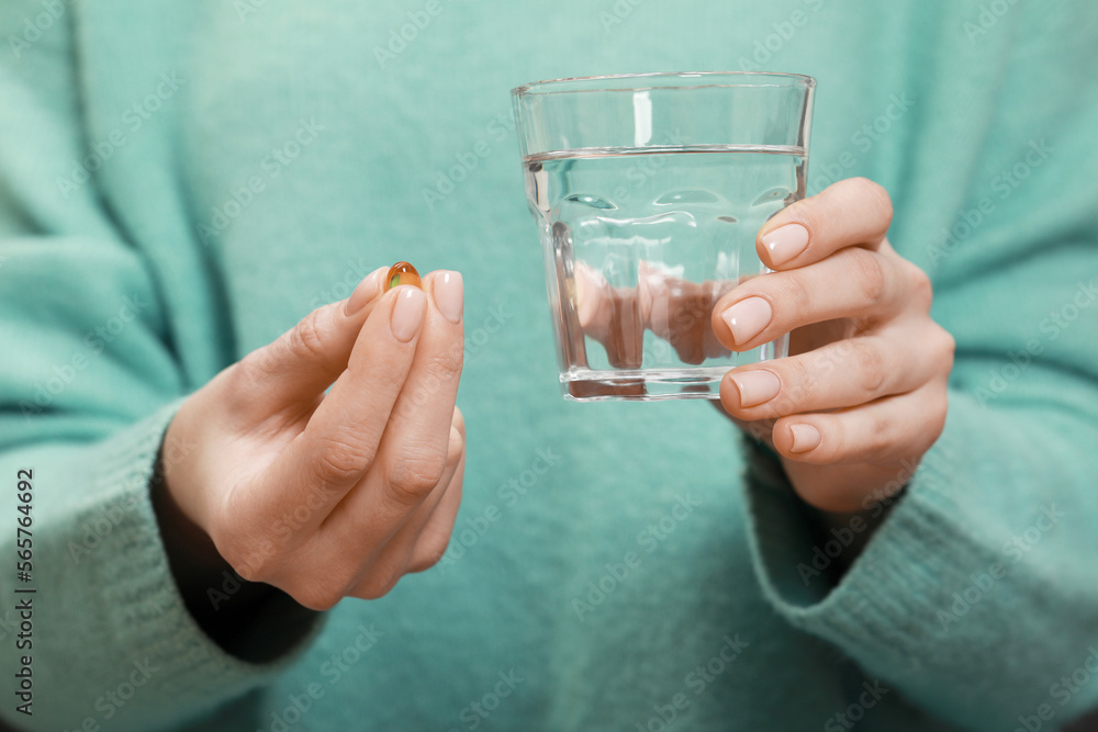 Woman holding glass of water and pill, closeup view Woman holding glass of water and pill, closeup view